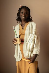 Sandra Gaffié tenant une figurine de repérage des méridiens, en tenue claire